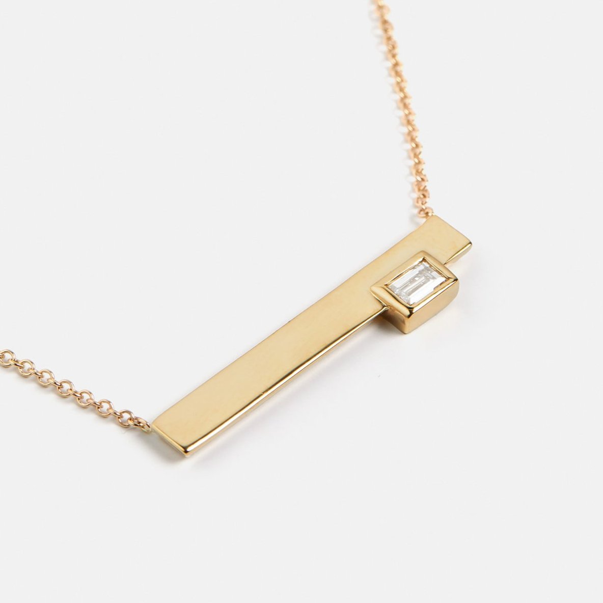 Cool necklace with delicate chain and asymmetrical pendant with lab created baguette white diamond in 14 karat gold SHW fine jewelry NYC