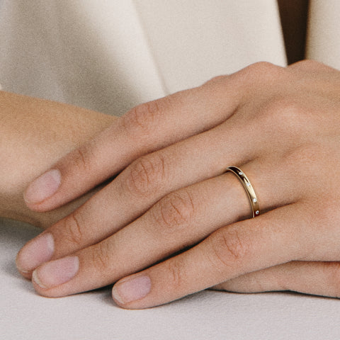 Minimal diamond band with unevenly spaced stones shown worn in natural light