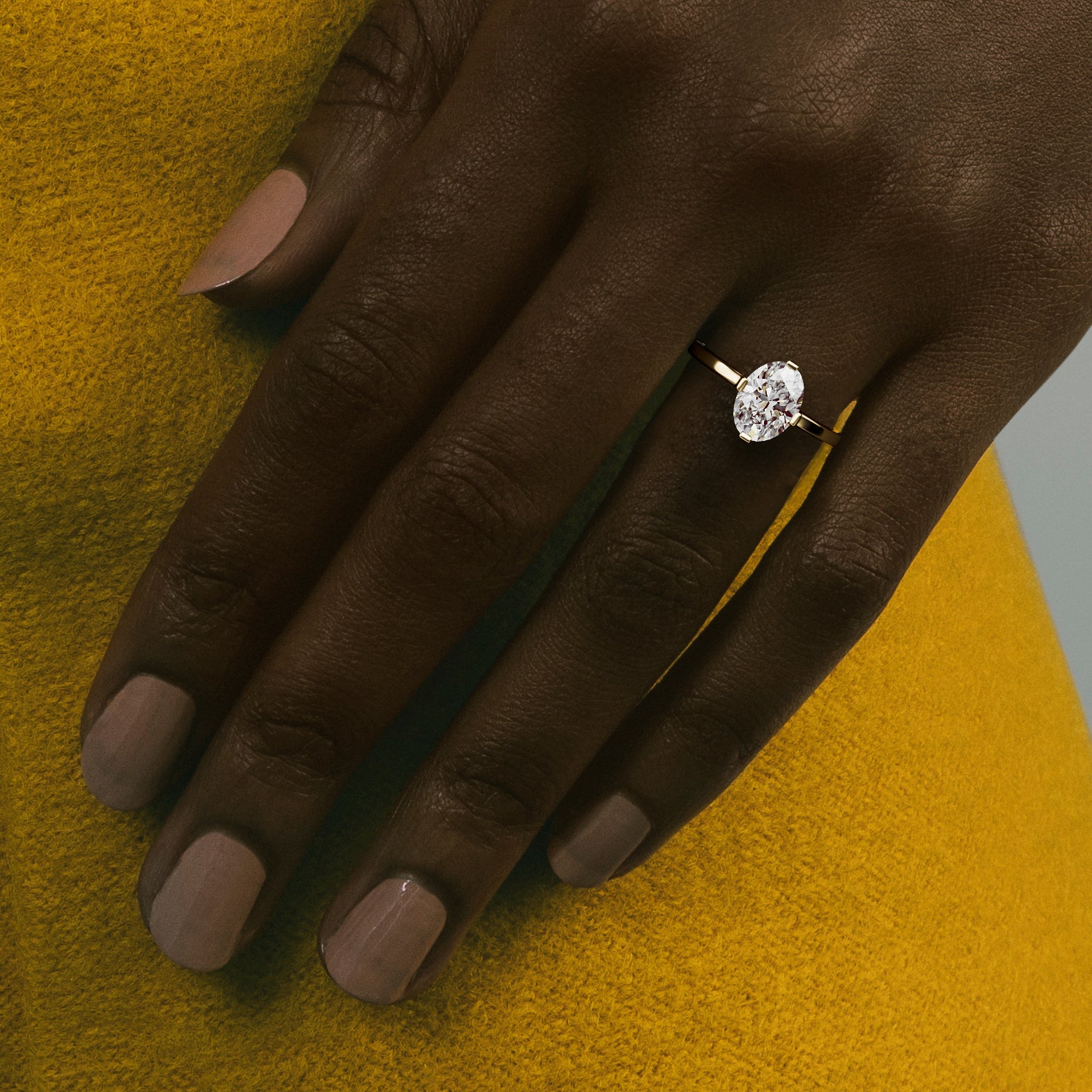 Dainty flat band oval engagement ring worn on hand