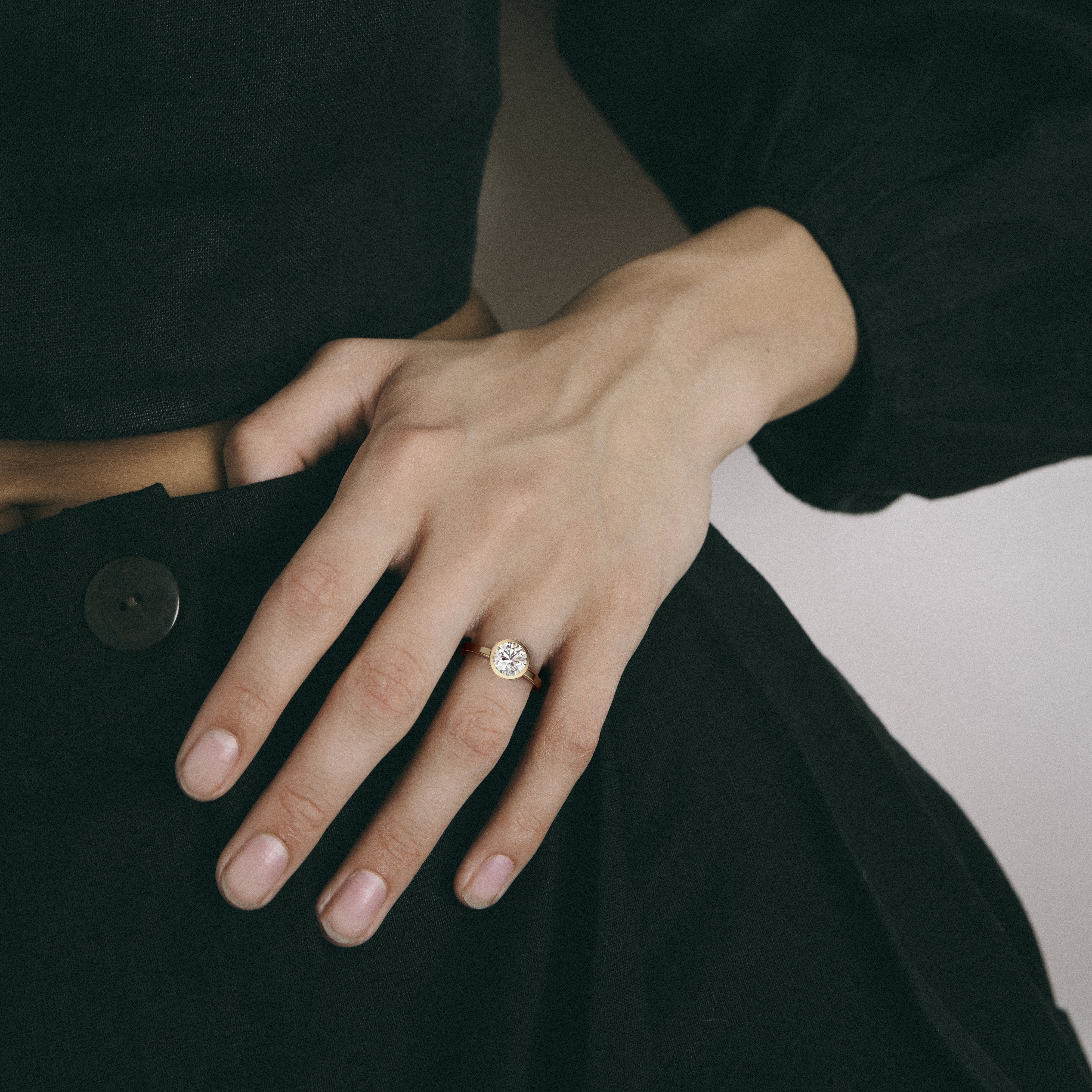 Minimal yellow gold engagement ring with bezel set round brilliant diamond worn on hand