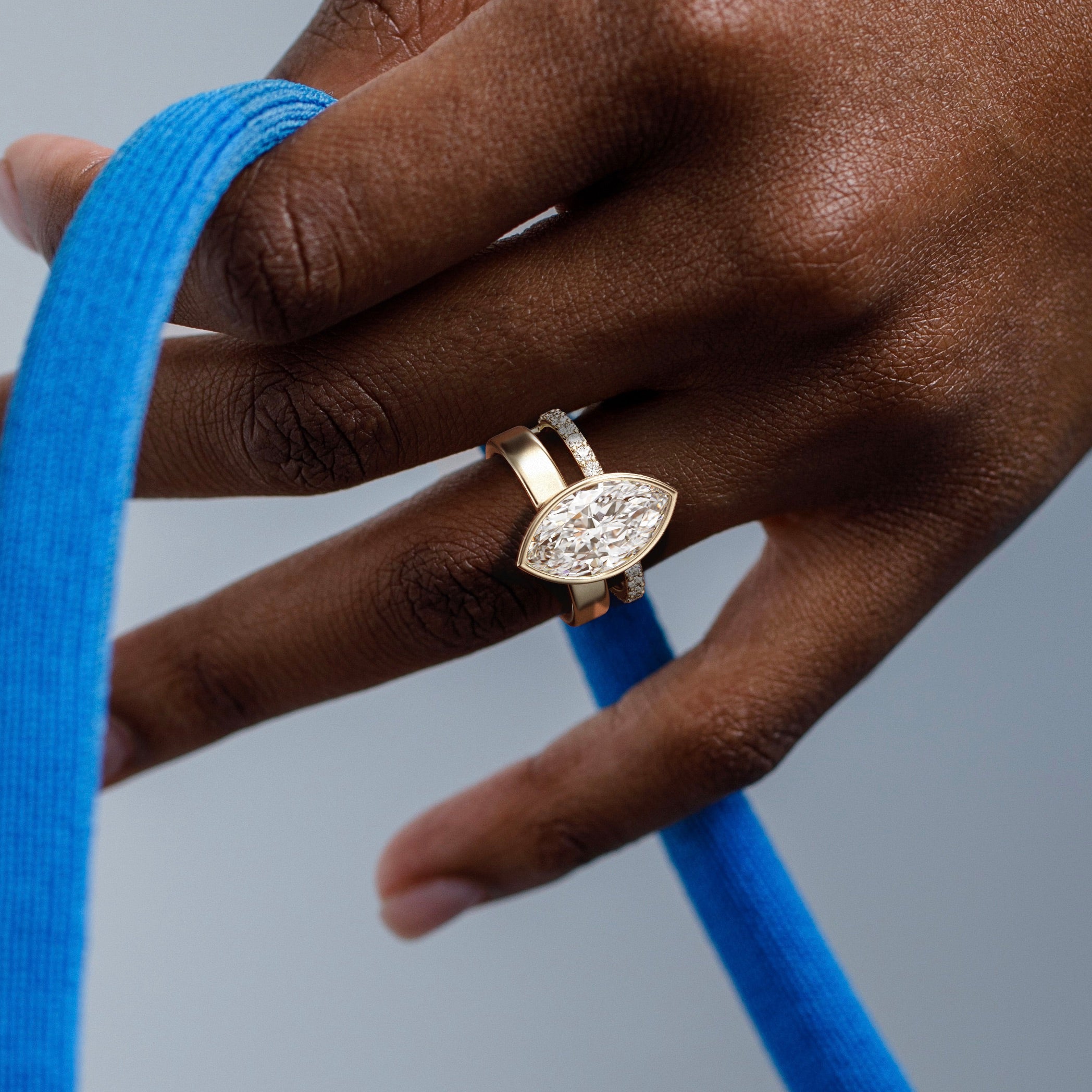 close view of 4 ct marquise diamond bezel engagement ring with pavé diamond eternity band on double band