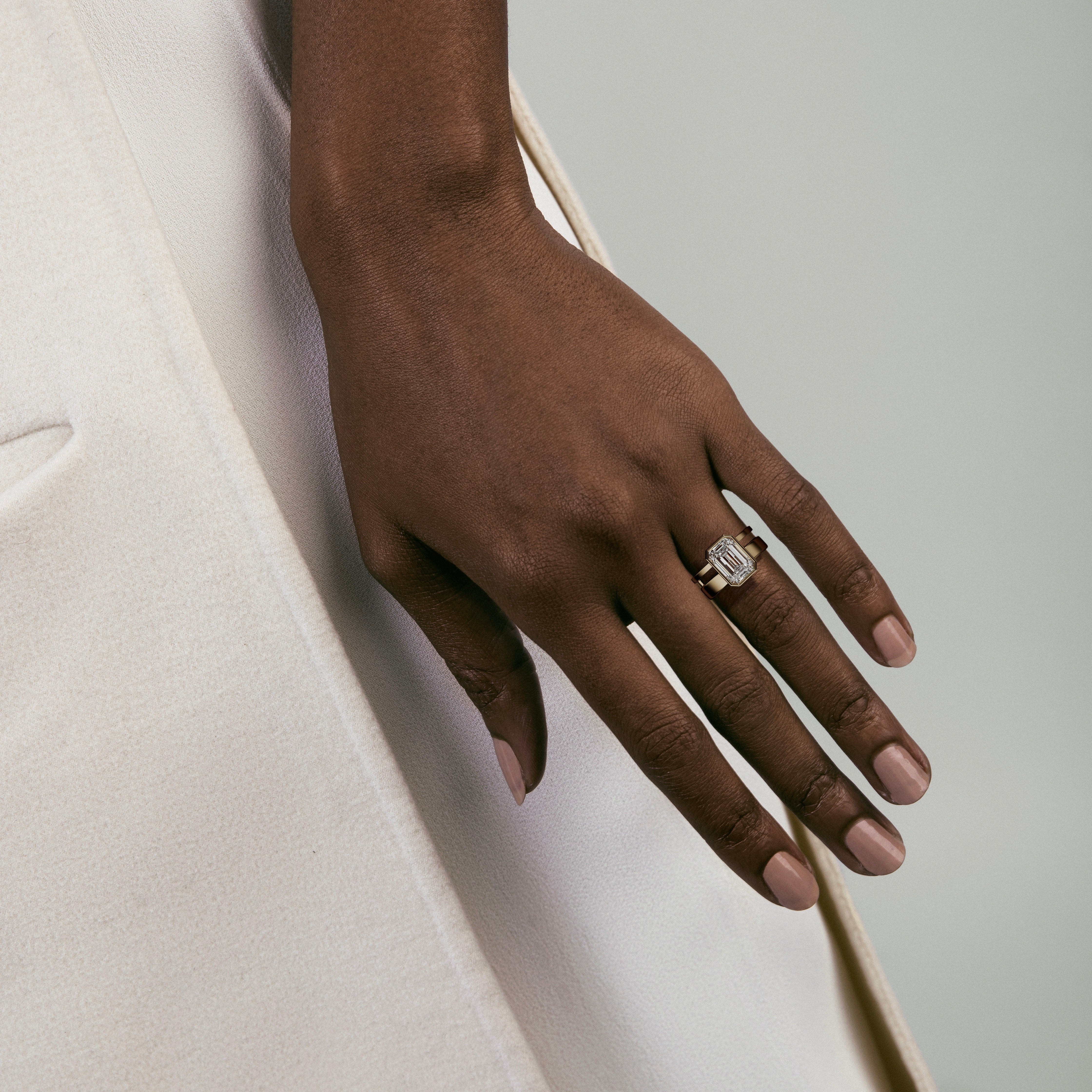 4.00 carat emerald-cut diamond engagement ring with bezel setting and sculptural double band worn on hand