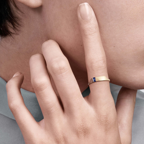 Delicate gold ring with baguette sapphire worn on hand