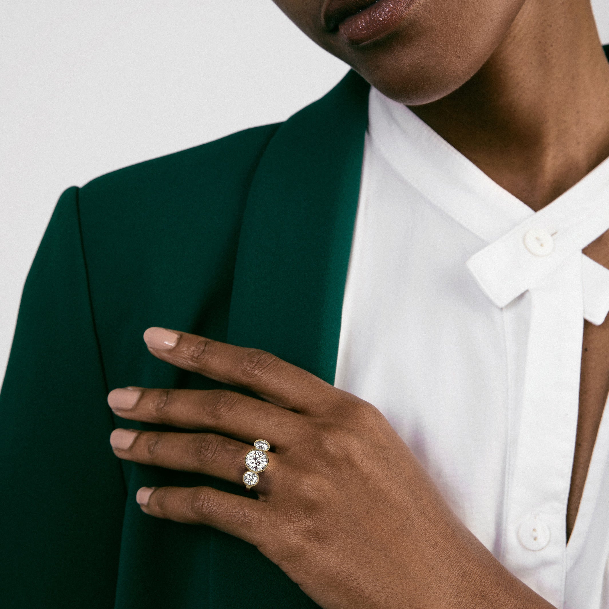 14k yellow gold three stone engagement ring with center diamond and side stones worn on hand