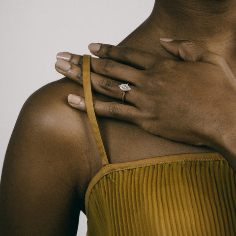 Dainty yellow gold engagement ring with marquise diamond worn on hand