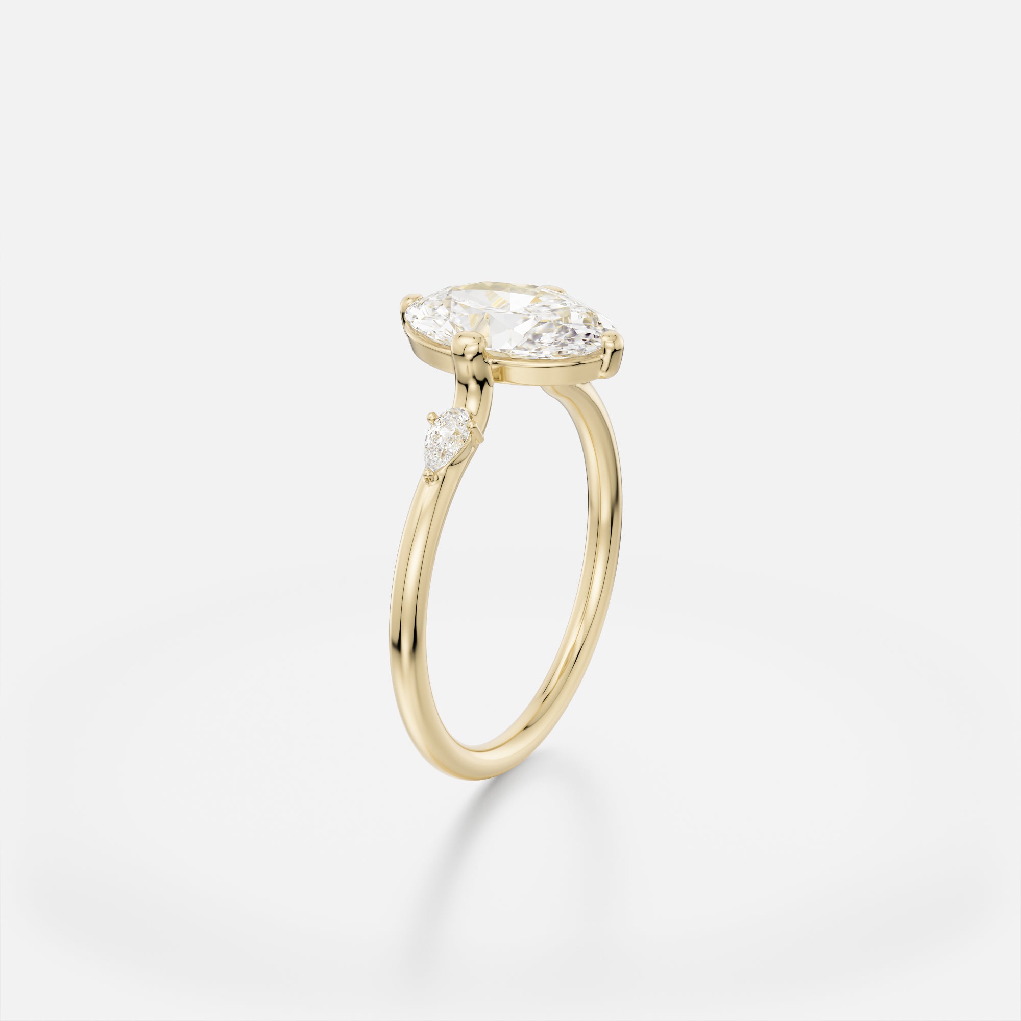 Delicate round band engagement ring with 2 ct north-south oval diamond and pear accent stones set along band
