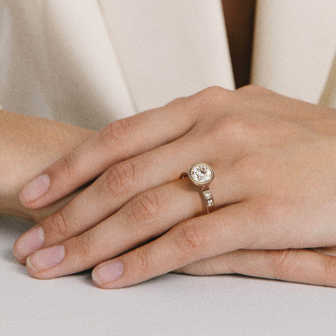 close view of round brilliant-cut diamond engagement ring with princess-cut diamonds flanking the center stone