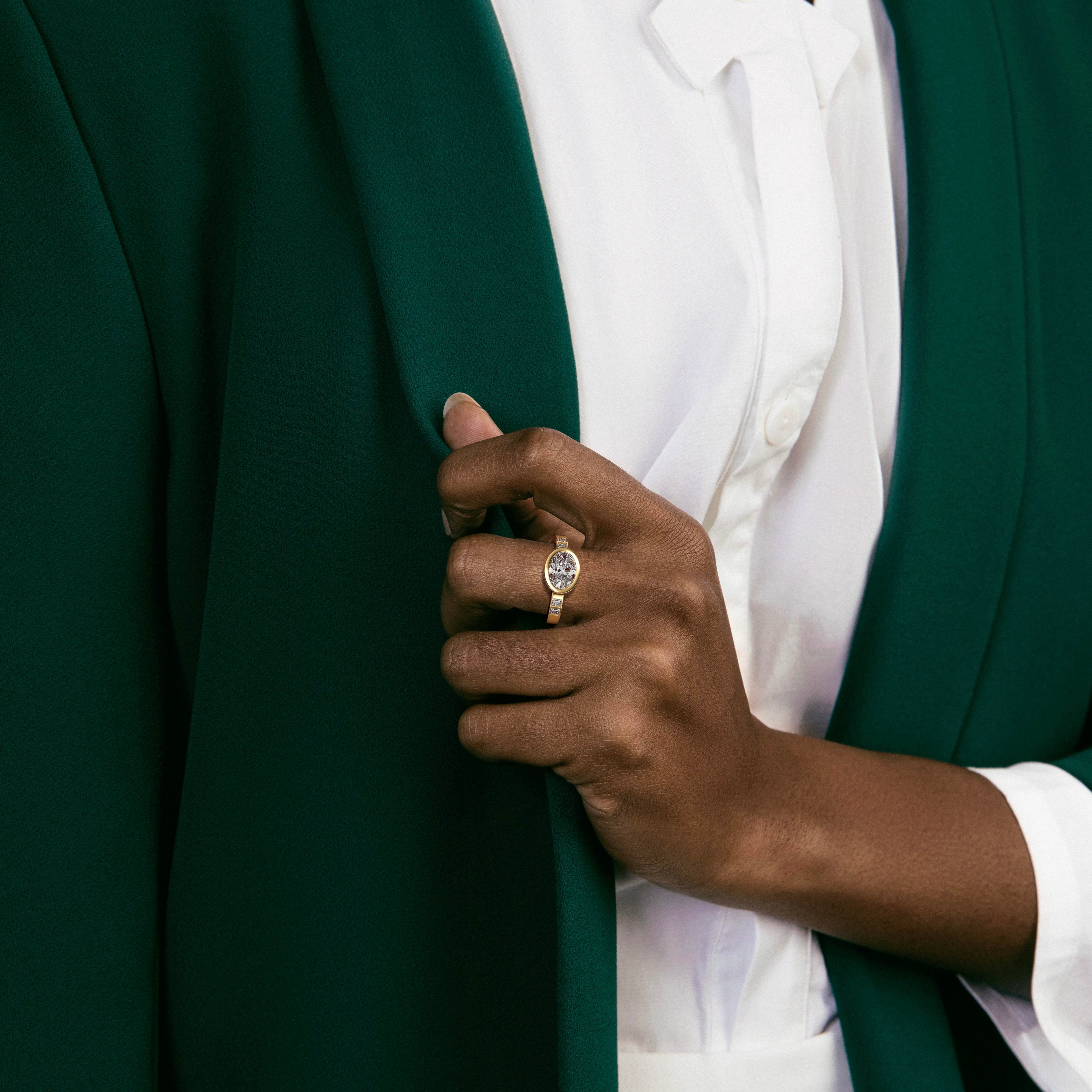 east west oval diamond engagement ring with princess-cut diamonds set along the band worn on hand