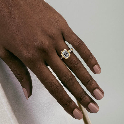 close view of emerald-cut diamond engagement ring with princess-cut diamonds flanking the center stone