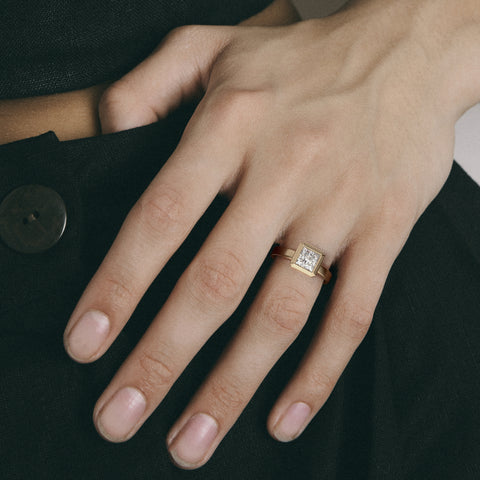 Close view of princess-cut diamond in thick bezel on wide flat band