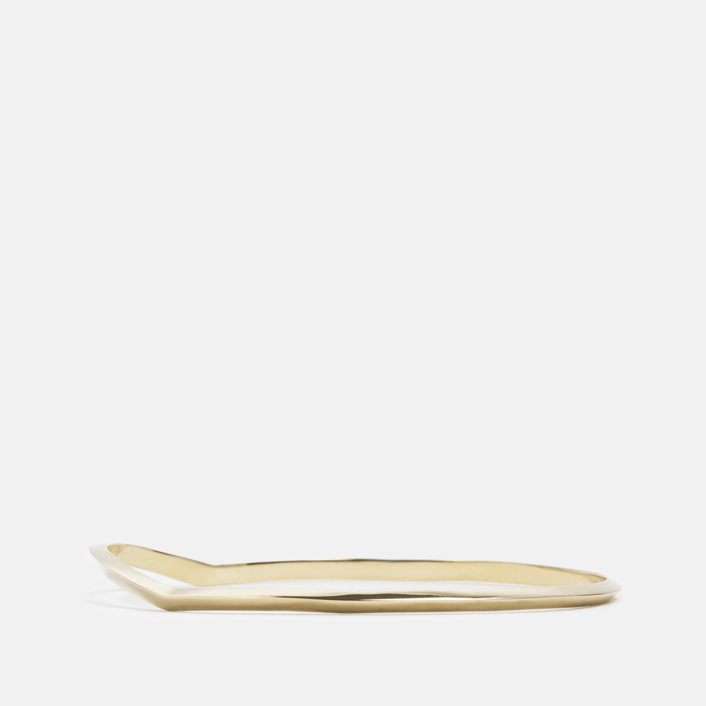 side profile of yellow brass bangle bracelet with tapered lines and subtle curved detail