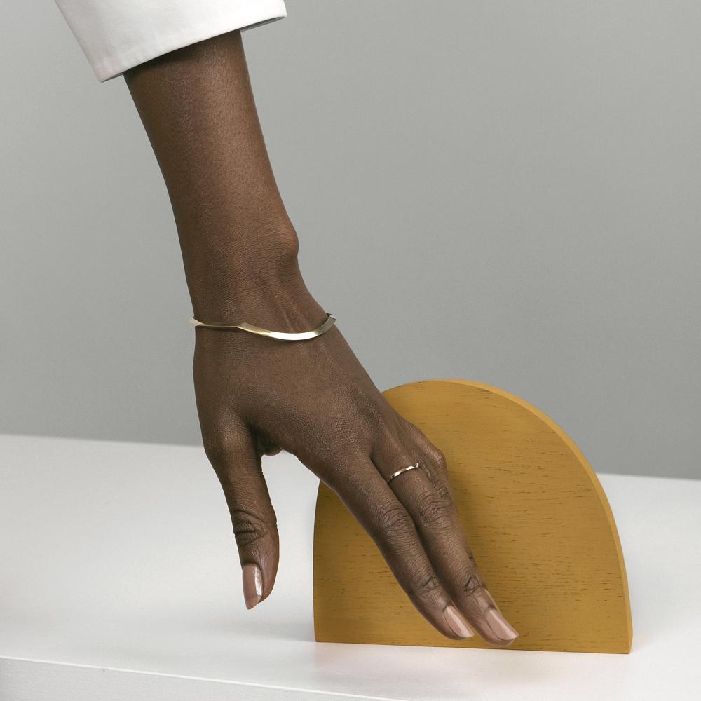 yellow brass sculptural bangle bracelet with tapered design worn on wrist in natural light