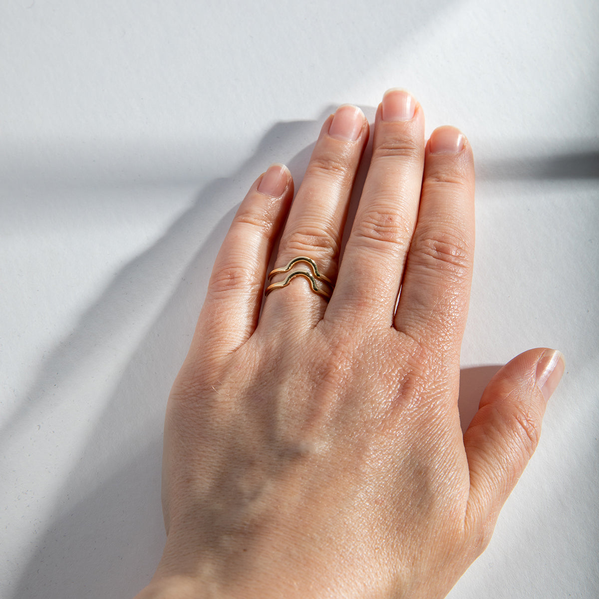 Dainty curved gold bands worn stacked on hand