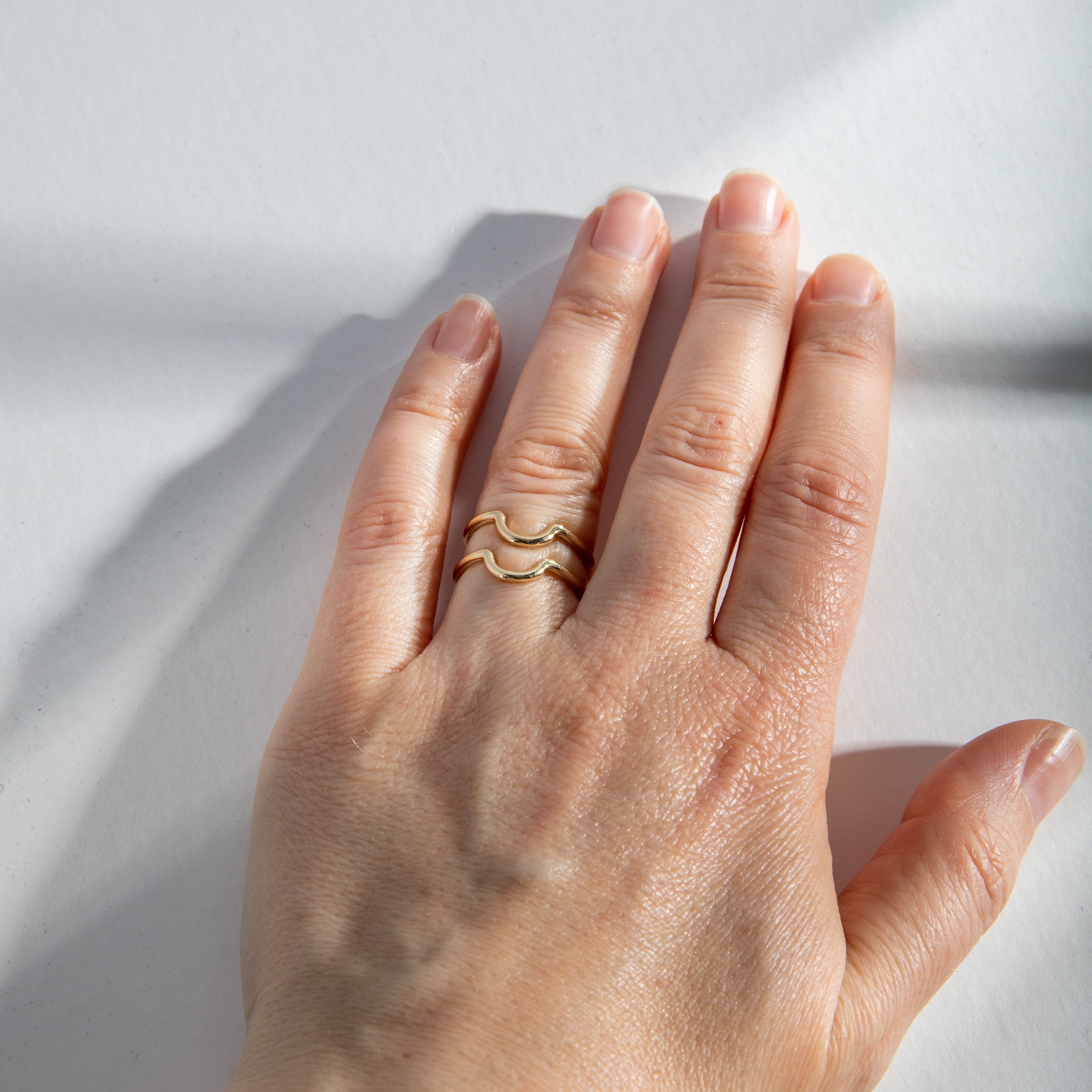 Two thin gold curved rings stacked together on hand